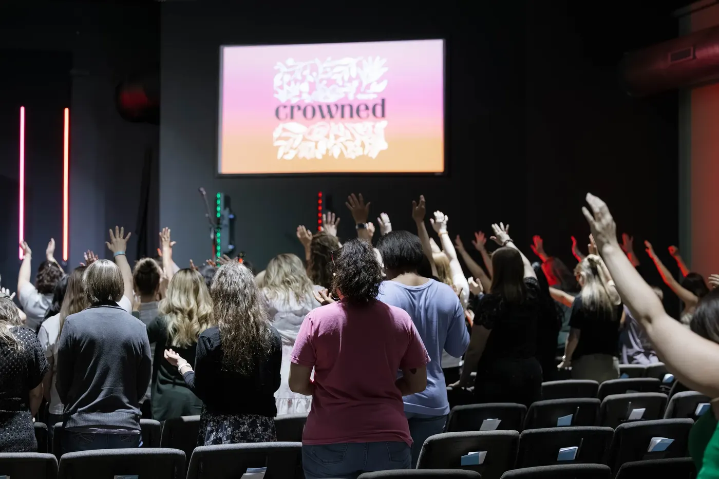 Women worshipping with hands raised at a Crowned night