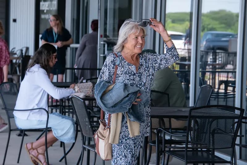 Una mujer sonriente llega a la entrada de Vintage Church en Harker Heights mientras otras personas conversan en el patio
