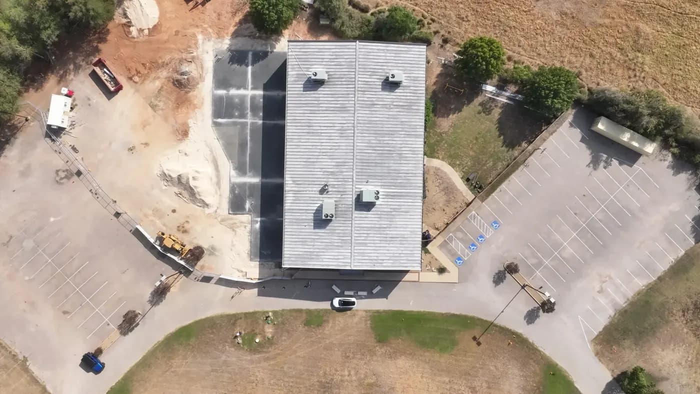 An overhead drone view of the Belton building with a new slab and construction equipment beside it