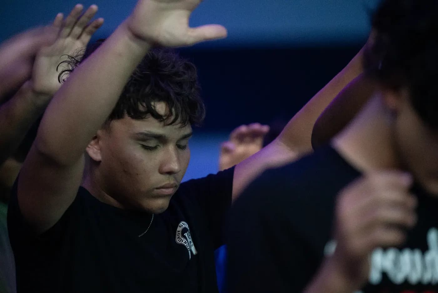 A student worshipping with one hand raised