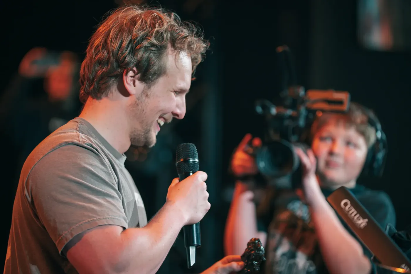 A camera operator filming a speaker on stage at the Forged Men's Conference