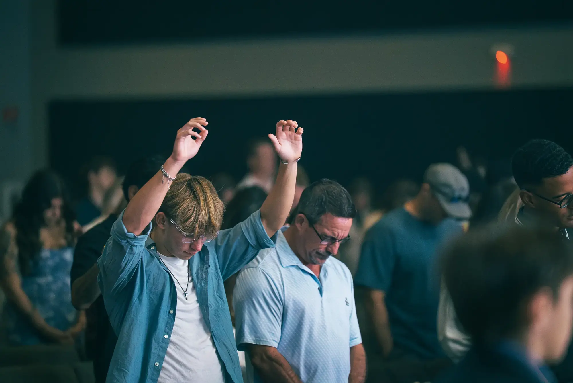 A Sunday service at Harker Heights, one worshipper with both hands raised beside another with head bowed