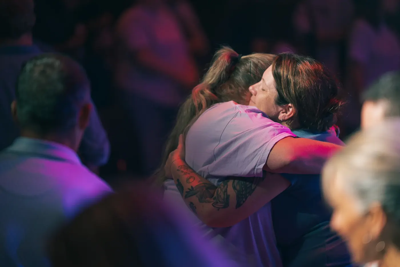 Two women embracing in prayer during a Sunday service