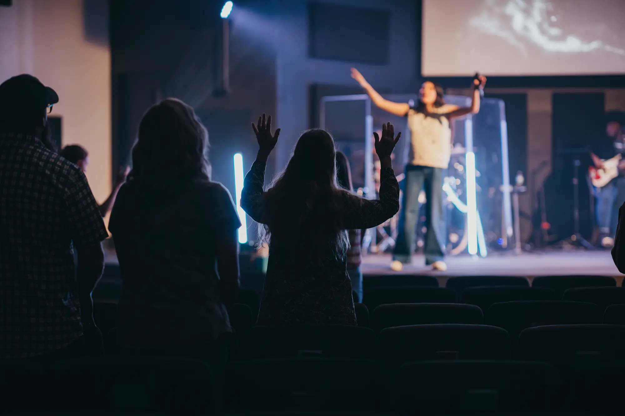 Hands raised in worship across the room