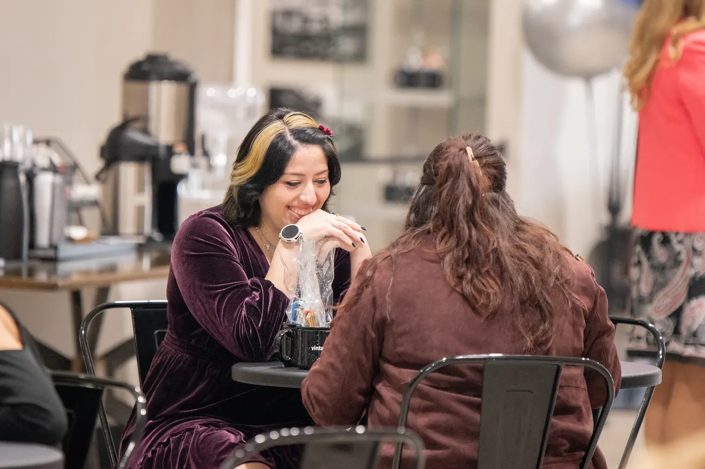 Two women talking over coffee at a café table in the lobby