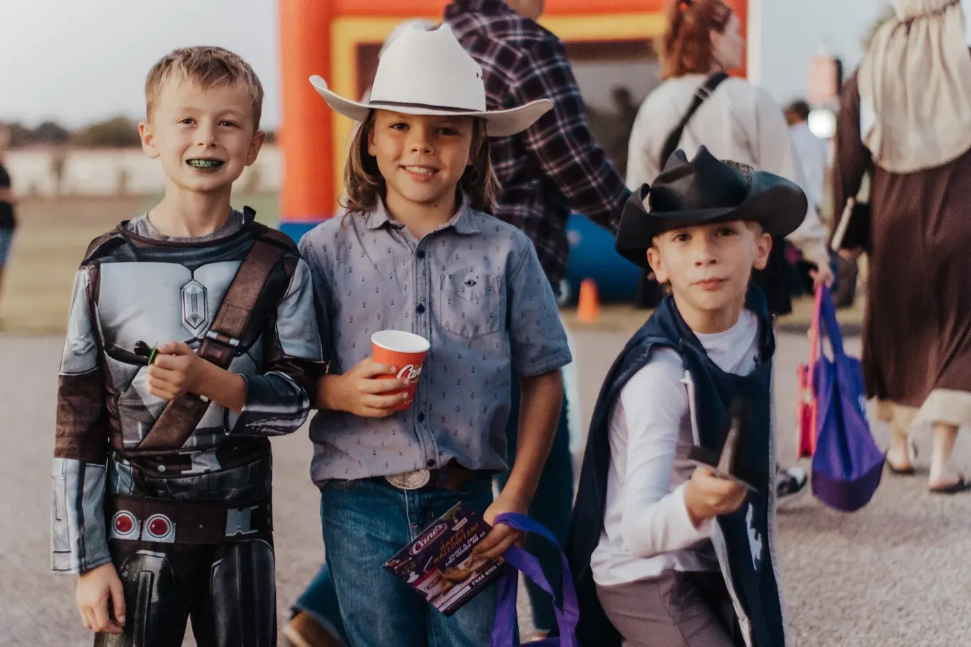Three boys in costume, a robot, a cowboy and a pirate, grinning with their candy