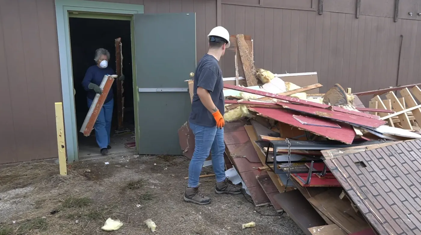 Facilities volunteers in hard hats clearing debris from a building renovation